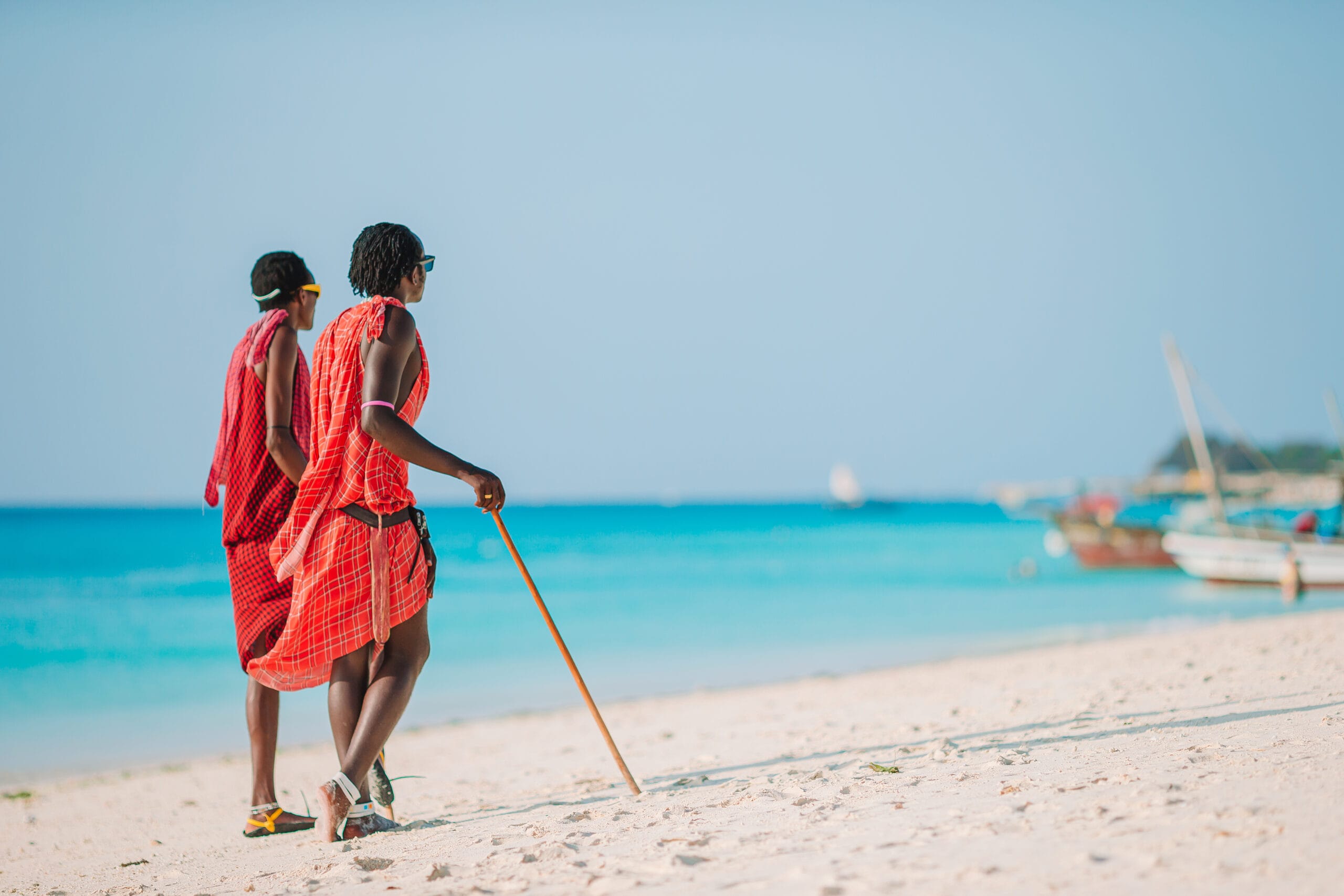 Two Masai dressed in traditional clothes walking along the beach on Zanzibar, Tanzania