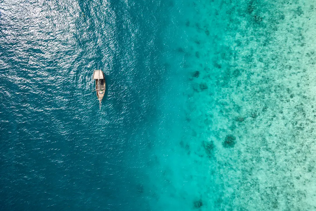 Aerial view of dhow boat sailing on Zanzibar tropical waters.